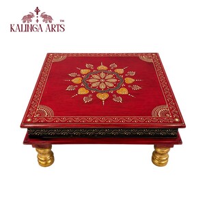 May include: A square wooden low table featuring a deep red surface with a central gold and black floral mandala pattern. The edges are decorated with intricate gold scrollwork, while the side panel is black with gold details and four gold legs.