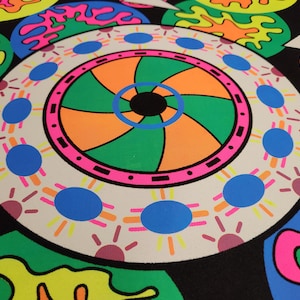 May include: A vibrant, abstract design featuring concentric circles and organic shapes in neon colors. The design includes orange, green, pink, blue, and yellow against a black background. The artwork has a psychedelic, retro feel.