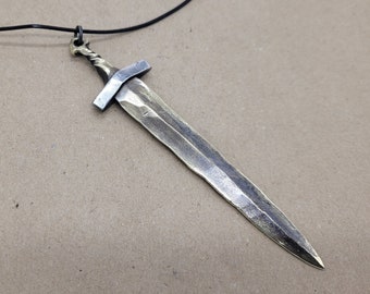 May include: A silver and gold sword pendant necklace. The sword has a simple design with a straight blade and a cross guard.