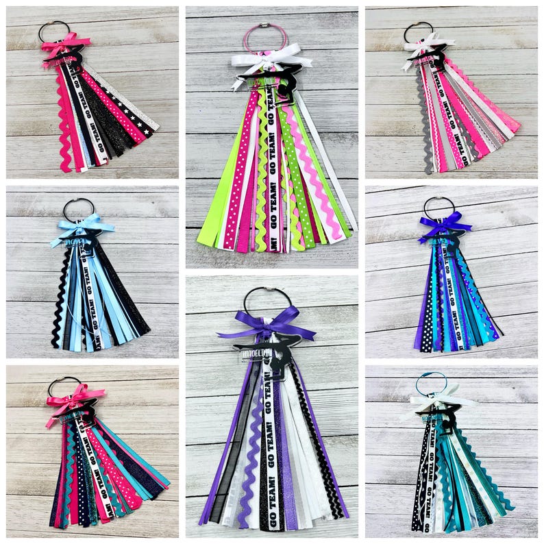 May include: Nine different hair ties with ribbons and a gymnast silhouette charm. The ribbons are in various colors and patterns, including black, white, pink, blue, green, purple, and teal. The charms are black and white. The hair ties are all tied with a bow.