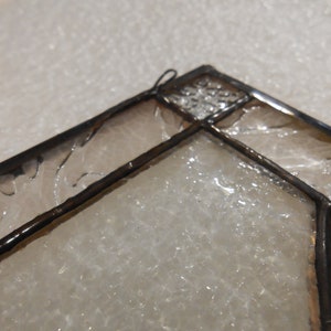 May include: Close-up of a stained glass window panel with a geometric design. The glass is clear and has a textured surface.