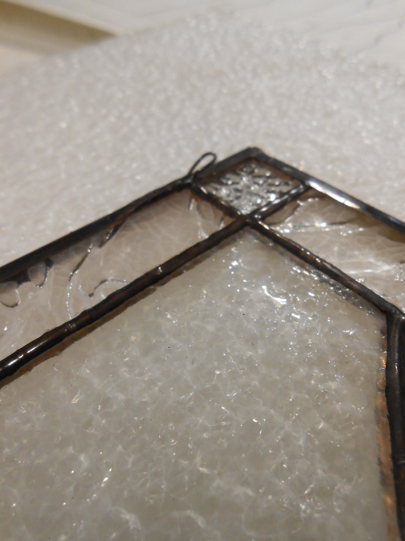 May include: Close-up of a stained glass window panel with a geometric design. The glass is clear and has a textured surface.