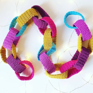 May include: A colorful crocheted garland made of linked loops in shades of pink, yellow, and blue. The garland is perfect for adding a touch of handmade charm to any space.