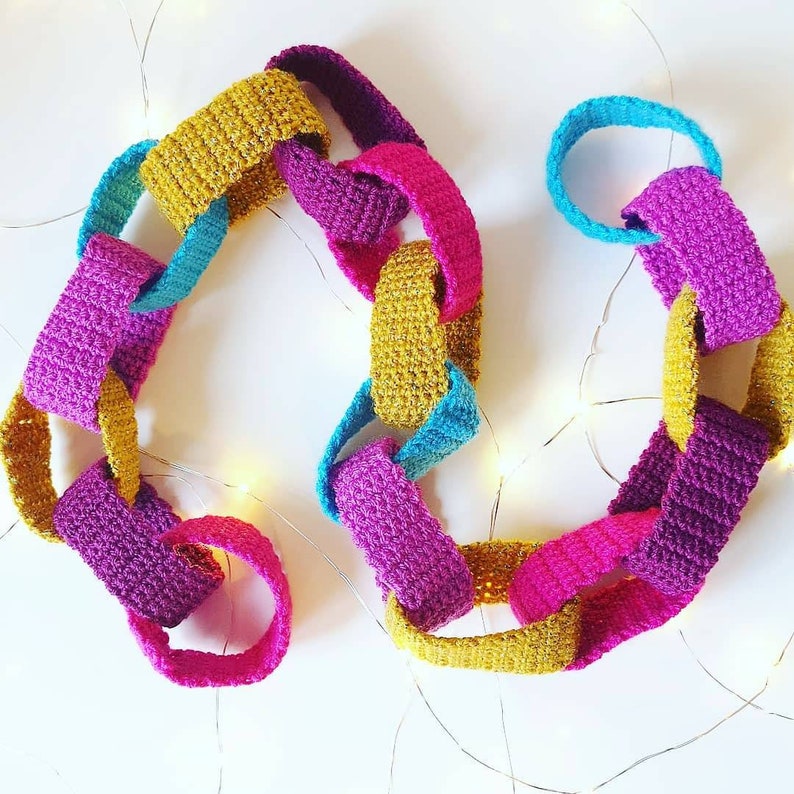 May include: A colorful crocheted garland made of linked loops in shades of pink, yellow, and blue. The garland is perfect for adding a touch of handmade charm to any space.