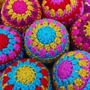 May include: A collection of colorful crocheted balls with a variety of patterns. The balls are made with pink, blue, yellow, and red yarn.