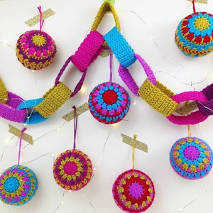 May include: A colorful crocheted garland with bright pink, blue, and yellow yarn. The garland is decorated with crocheted ornaments in various colors, including red, pink, blue, and yellow.