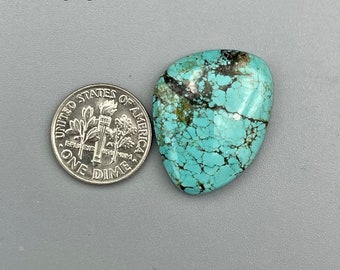 Può includere: Un cabochon turchese con una matrice marrone scuro. La pietra è circa delle dimensioni di una moneta da dieci centesimi di euro. La pietra è etichettata con il numero 823.