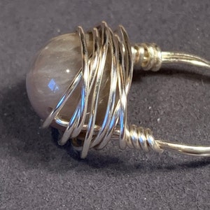May include: A silver wire wrapped ring with a light gray gemstone.