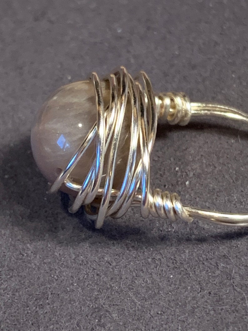 May include: A silver wire wrapped ring with a light gray gemstone.