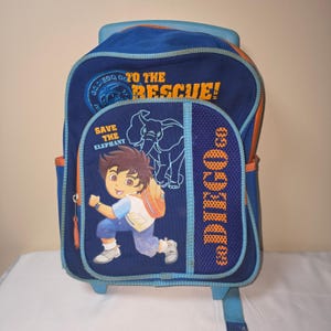 May include: Blue rolling backpack featuring the character Diego from "Go, Diego, Go!" with the text "Go, Diego, Go! To the Rescue!" and "Save the Elephant." The backpack has orange accents, a mesh side pocket, and a blue handle.
