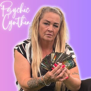 May include: A woman with long blonde hair holds a deck of tarot cards. The image has a purple and pink gradient background. The text "Psychic Cynthia" is written in a cursive font in the upper left corner.