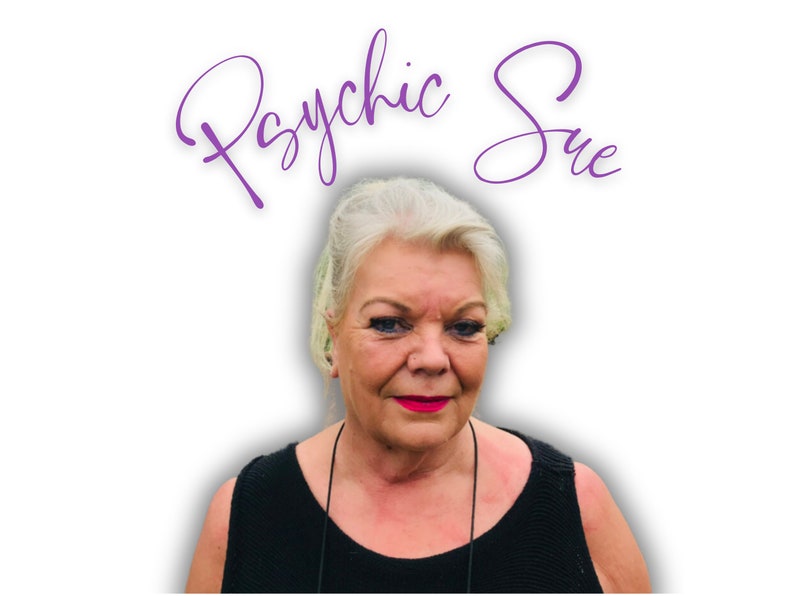 May include: A woman with white hair and red lipstick is smiling at the camera. The text "Psychic Sue" is written in purple cursive above her head.