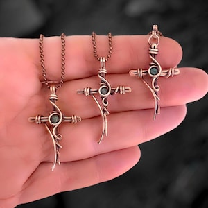 Könnte beinhalten: Drei Halsketten aus Kupferdraht mit grünen Steinen. Jedes Kreuz hat ein einzigartiges Design mit Schnörkeln und Kurven.