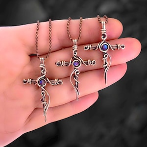 May include: Three silver wire wrapped cross pendants with iridescent blue gemstones. Each cross is on a silver chain.