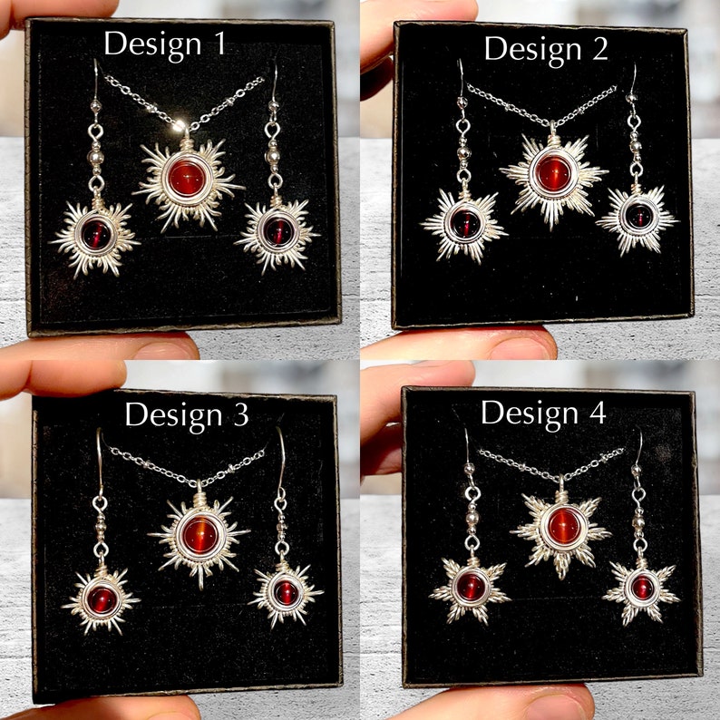 May include: Four designs of jewelry sets featuring a red gemstone sun pendant and matching earrings. Each set is displayed in a black box with the design number labeled on the top.