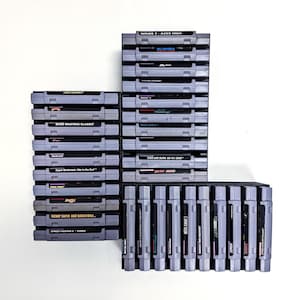 May include: A collection of gray Super Nintendo game cartridges, stacked in black holders. Titles visible include "Wings 2: Aces High," "Bass Masters Classic," and "Tecmo Super NBA Basketball." The cartridges are arranged against a white background.