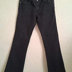 K&ouml;nnte beinhalten: Schwarze Jeans mit leicht ausgestelltem Bein. Die Jeans hat einen Knopf- und Rei&szlig;verschluss, Vorder- und Ges&auml;&szlig;taschen, und der Markenname "Rock & Republic" ist am Bund sichtbar.