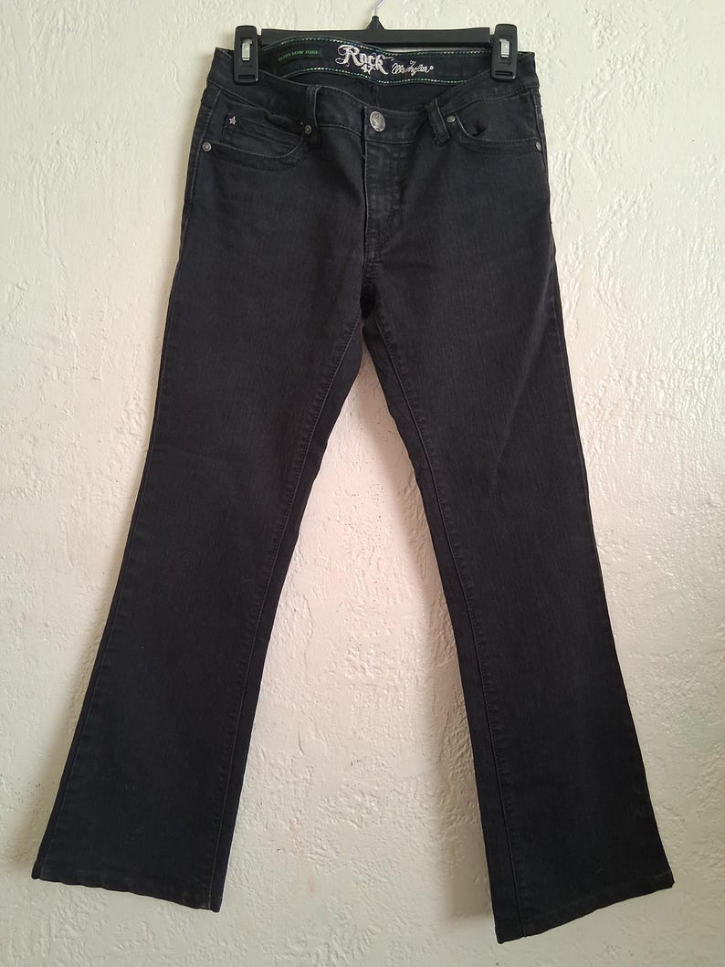 K&ouml;nnte beinhalten: Schwarze Jeans mit leicht ausgestelltem Bein. Die Jeans hat einen Knopf- und Rei&szlig;verschluss, Vorder- und Ges&auml;&szlig;taschen, und der Markenname "Rock & Republic" ist am Bund sichtbar.