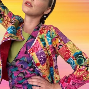 Può includere: Una giacca colorata in patchwork con stampa floreale e geometrica. La giacca ha una fodera rossa e una chiusura con bottoni. La giacca è realizzata in un tessuto leggero e ha una vestibilità rilassata.