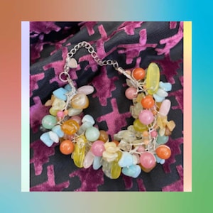 Könnte beinhalten: Ein farbenfrohes Perlenarmband mit verschiedenen Steinen, darunter Aquamarin, Amethyst und Citrin. Das Armband ist aus Silberdraht gefertigt und hat einen herzförmigen Anhänger.