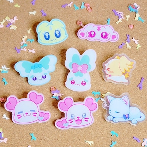 Op de afbeelding: Een verzameling kleurrijke cartoonkarakterstickers in verschillende vormen, waaronder een beer, wolk, konijn en kat. De stickers zijn voornamelijk pastelkleuren met schattige gezichtsuitdrukkingen. Kleine decoratieve vormen zijn verspreid.