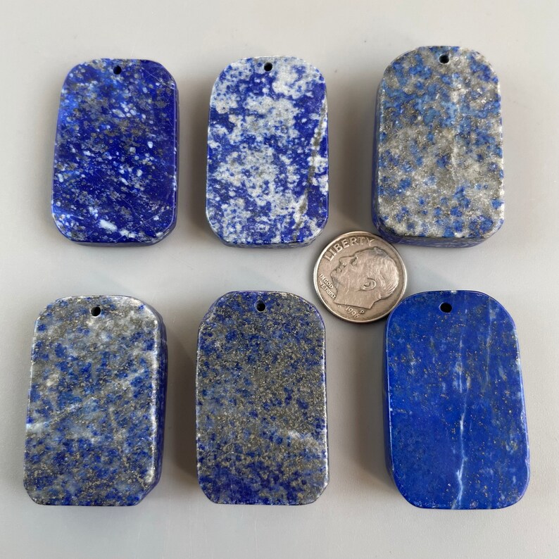 May include: Six rectangular lapis lazuli pendants with gold flecks. The pendants have a hole at the top for stringing.