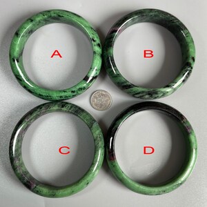 May include: Four green and black gemstone bangles with a silver coin for scale. The bangles are labeled A, B, C, and D.