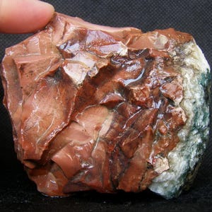 May include: A large, rough, red and white agate stone with a green and white agate section. The stone has a natural, polished finish.