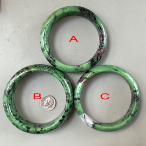 Puede incluir: Tres pulseras de piedra preciosa de color verde, negro y blanco. Las pulseras están dispuestas en forma de triángulo, con la más grande en la parte superior. Las pulseras son de diferentes tamaños y tienen un patrón único.