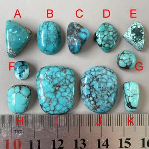May include: Ten turquoise cabochons of varying sizes and shapes, labelled A through K. The cabochons are arranged in two rows on a grey surface. A ruler is placed below the cabochons, with markings from 10 to 16 centimetres.