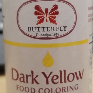 May include: A 1 fluid ounce bottle of dark yellow food coloring. The bottle is labeled "Dark Yellow Food Coloring" and features a butterfly logo with the text "BUTTERFLY Gunacipta 1948".
