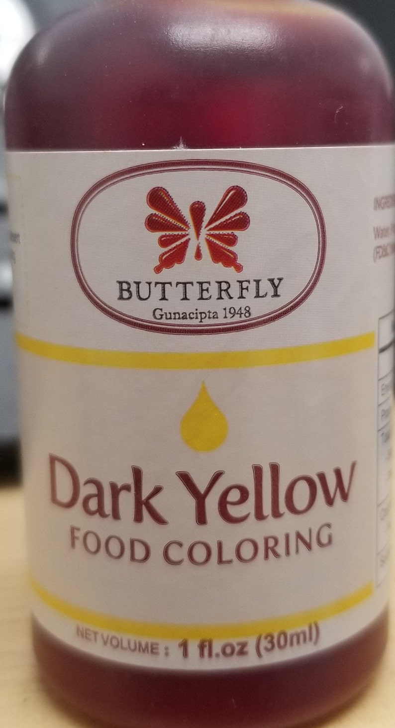 May include: A 1 fluid ounce bottle of dark yellow food coloring. The bottle is labeled "Dark Yellow Food Coloring" and features a butterfly logo with the text "BUTTERFLY Gunacipta 1948".