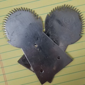 May include: Two silver pineapple peelers with serrated edges and a handle. The peelers are made of stainless steel and have a small hole in the handle.