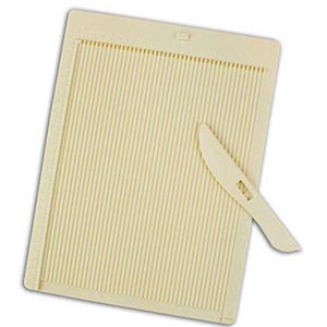 May include: A cream-colored paper scoring board with vertical grooves and a small, matching knife. The board has a rectangular shape with a ruler along the side. The knife is used for scoring paper for crafts.