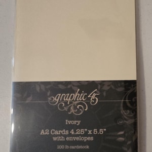 May include: A package of ivory A2 cards with envelopes. The package has a dark background with the words "graphic 45" and "Ivory" printed on it. The cards measure 4.25" x 5.5" and are made of 100 lb cardstock.