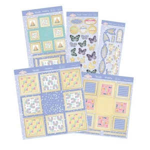 May include: Four sheets of decorative paper and stickers featuring pastel colors and patterns. Designs include rainbows, birthday cakes, butterflies, and bows. The sheets have a light purple background with white stars and gold-toned borders.