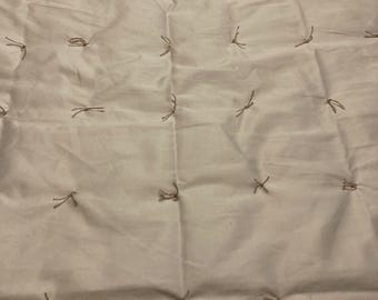 May include: A white quilted fabric with brown stitching in a grid pattern.