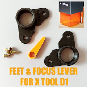 May include: Two black 3D printed feet and a focus lever for an XTOOL D1 3D printer. The feet have a round hole in the center and the lever is a small orange piece with a hole in the center. There are also four small gold screws.
