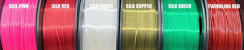May include: Six spools of filament for 3D printing in various colors, including pink, red, white, copper, green, and red. The filament is labeled with the names "Silk Pink", "Silk Red", "Silk White", "Silk Copper", "Silk Green", and "Twinkling Red".