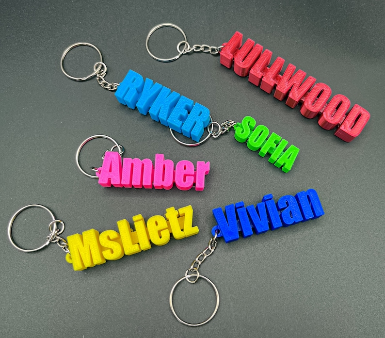 May include: Five colorful keychains with different names on them. The names are Ryker, Sofia, Amber, Mslietz, and Vivian. The keychains are made of plastic and have a silver metal ring.