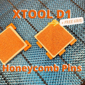 May include: Two orange and tan honeycomb pins with the text "XTOOL D1" and "Honeycomb Pins" on a blue grid background. The pins have a square shape with a cork-like texture and orange corner pieces. A white banner reads "+ FREE GRID".