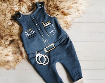 May include: A dark blue heathered sleeveless romper featuring a printed police uniform design. The front displays the text Kinder POLIZEI, a pocket with a radio, a belt with a buckle, and handcuffs. The number 110 is printed on the pocket.