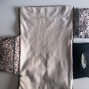 May include: A white zippered pouch with two pink and black heart patterned pouches attached. The pouches are lined with black fabric and have a zipper closure.