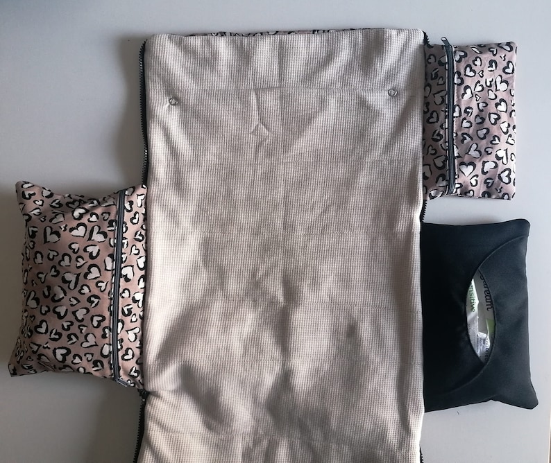 May include: A white zippered pouch with two pink and black heart patterned pouches attached. The pouches are lined with black fabric and have a zipper closure.