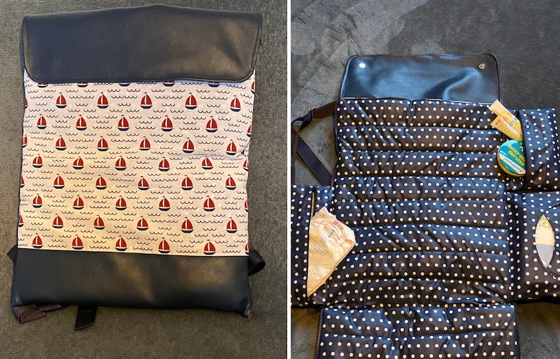 May include: A black and white polka dot changing mat with a black faux leather flap. The mat has multiple pockets and is folded open to reveal the interior. The mat is designed for changing babies.