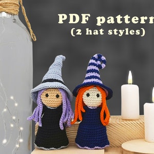 Può includere: Modello PDF per lavorare a uncinetto due bambole streghe con diversi stili di cappello. Una bambola ha un cappello viola con una striscia bianca e l'altra un cappello blu semplice. Entrambe le bambole hanno i capelli lunghi e indossano abiti neri.