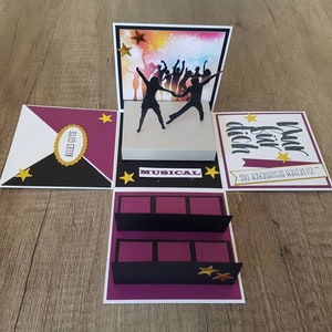 Könnte beinhalten: Eine handgefertigte Pop-up-Karte mit einem musikalischen Thema. Die Karte zeigt eine Bühne mit tanzenden Silhouetten, Sternen und dem Wort "MUSICAL". Zusätzlicher Text enthält "ALLES GUTE" und "Nur für dich". Die Karte ist in den Farben Lila, Schwarz, Weiß und Gold gehalten.