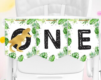 Könnte beinhalten: Ein weißer Hochstuhl-Banner mit grünen Blättern und goldenem Glitzer. Der Banner sagt "ONE" in Schwarz mit einer goldenen Dinosaurier-Silhouette auf dem ersten Buchstaben.