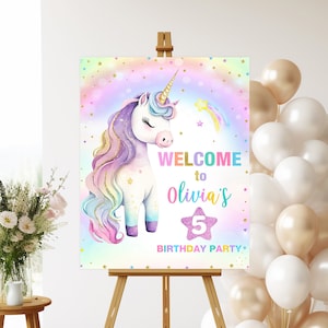 May include: A welcome sign for a unicorn-themed birthday party. The sign features a rainbow background with a white unicorn with a rainbow mane and tail. The text on the sign reads "Welcome to Olivia's 5th Birthday Party".