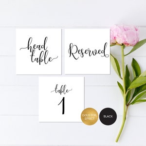 May include: Three white cards with black calligraphy. The first card says "head table", the second card says "Reserved", and the third card says "table 1".
